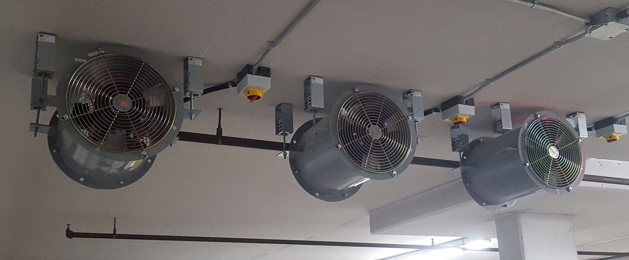 Ceiling-mounted axial ventilation fans in a parking structure